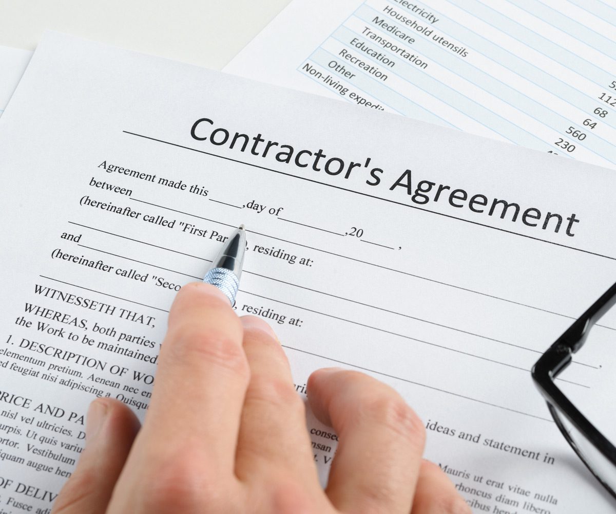 Hand-pointing-a-pen-on-an-independent-contractor’s-agreement