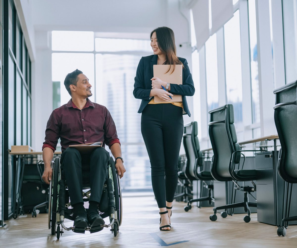 Male-employee-in-a-wheelchair-speaking-to-female-colleague