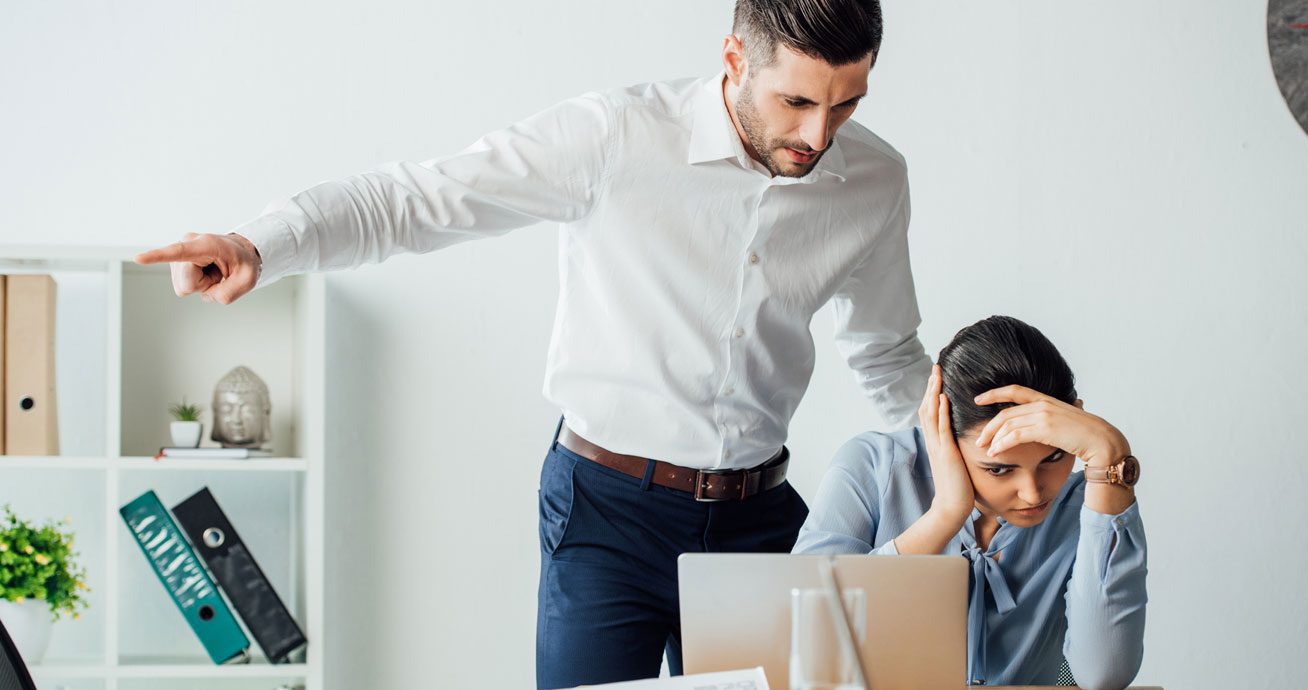 Businessman-pointing-finger-near-seated-colleague-during-office-discussion