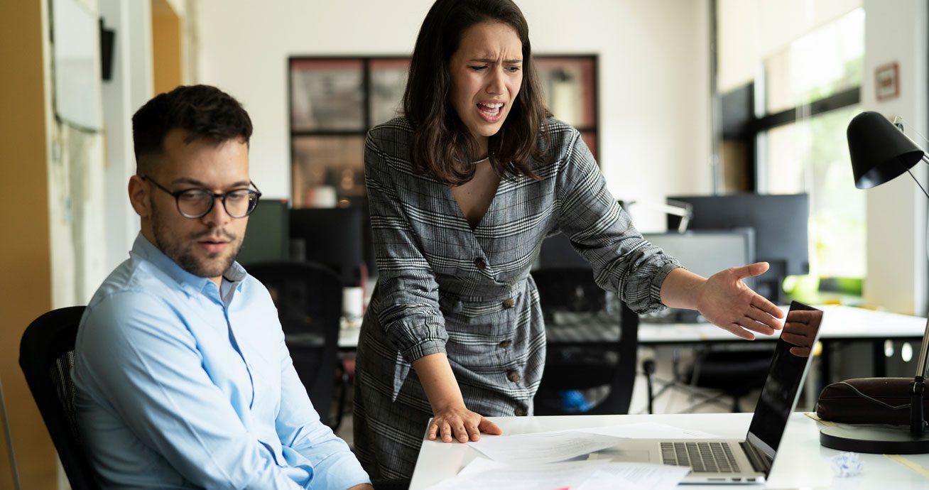 Group-of-coworkers-in-tense-discussion-around-seated-colleague