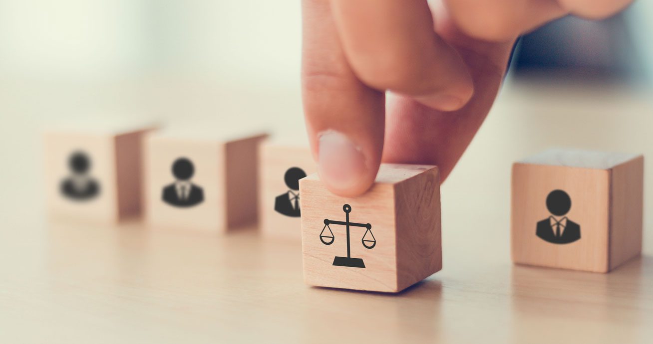 Hand-placing-wooden-block-with-scales-of-justice-icon