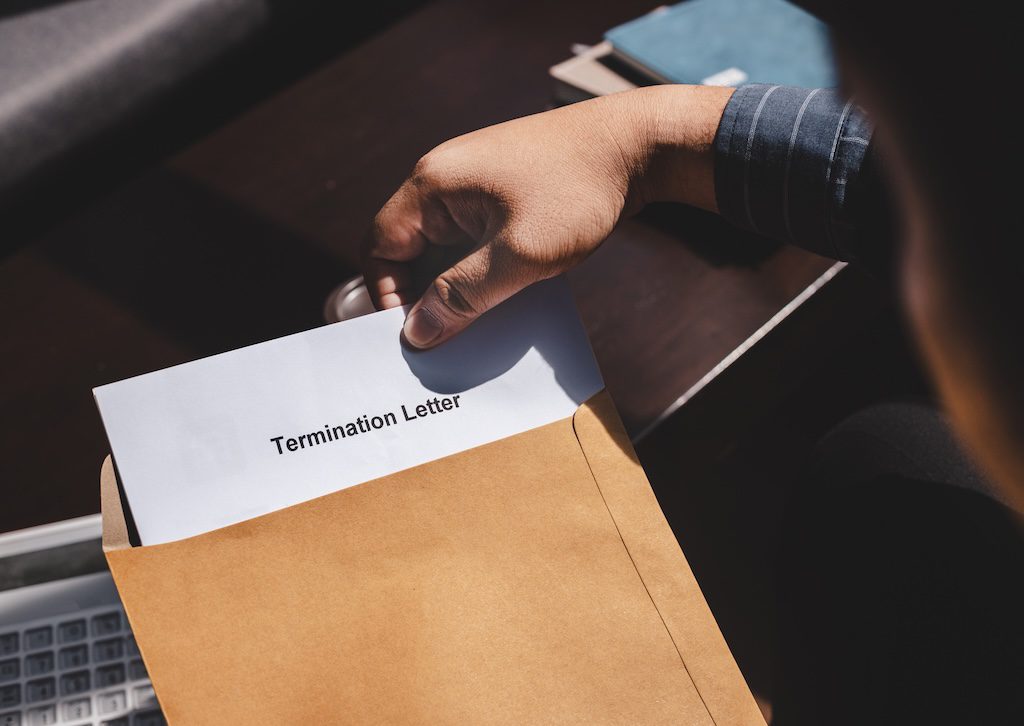 person-handing-over-a-termination-letter-in-an-envelope