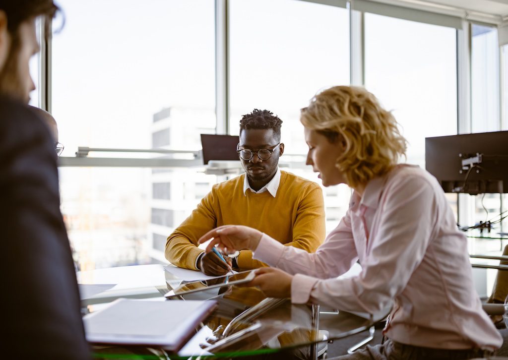 three-people-meeting-at-a-table-in-a-bright-office
