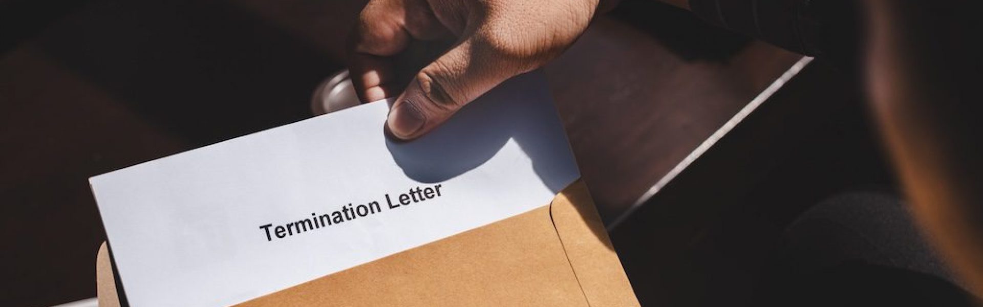 person-handing-over-a-termination-letter-in-an-envelope